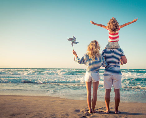 Happy family on the beach. People having fun on summer vacation. Father, mother and child against blue sea and sky background. Holiday travel concept